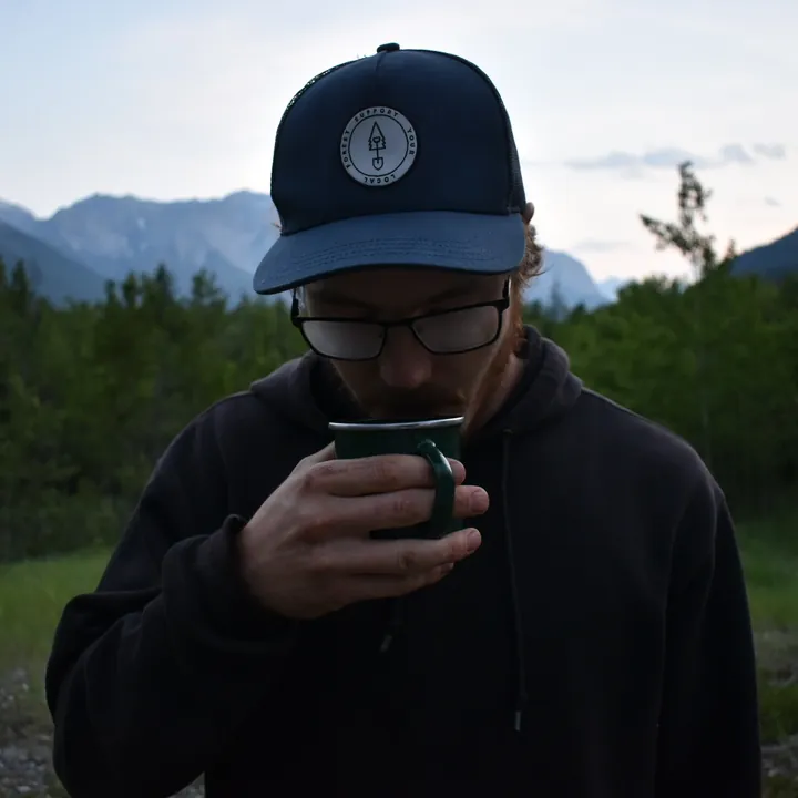 Brandon Raso drinking coffee at a mountain camp at dusk